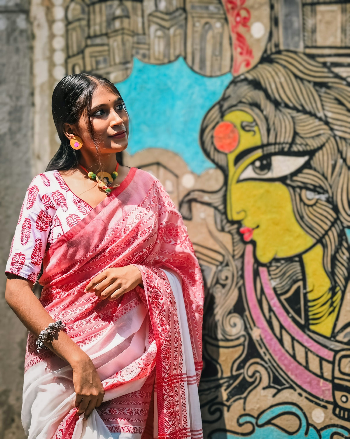 A woman standing in front of a wall with a painting on it