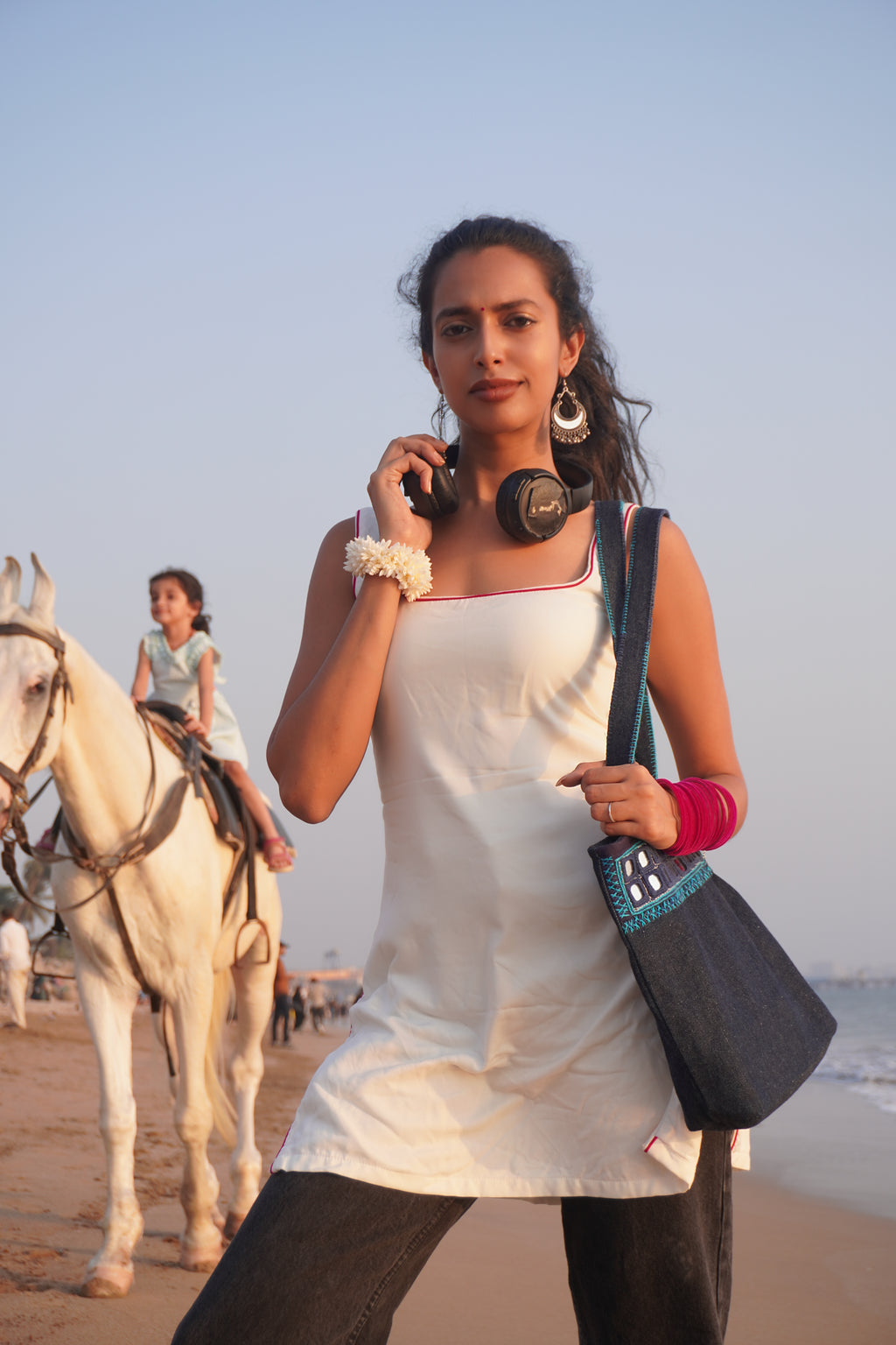 Ria Nalavade in a white Bindee Tank Top Kurti standing at Versova beach with a horse in the background