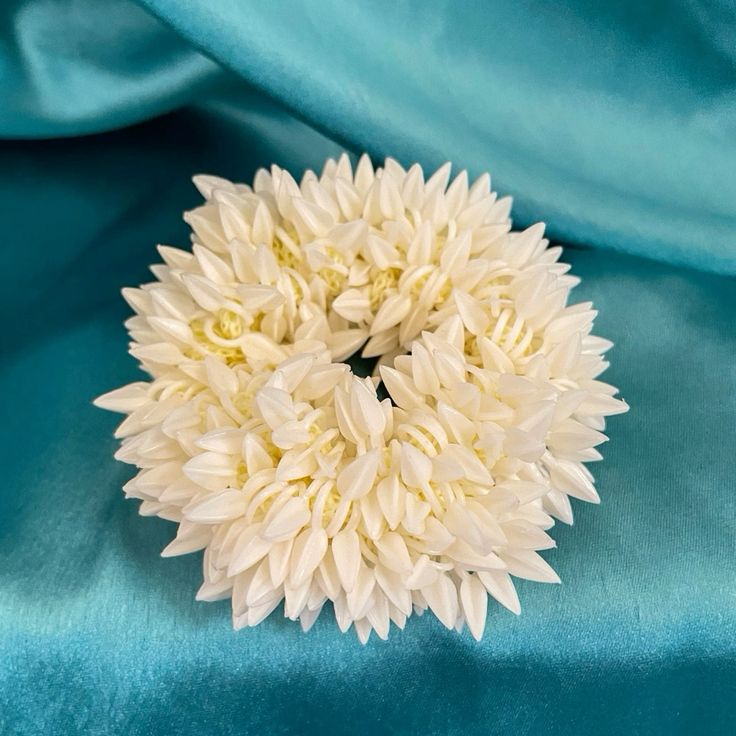 Bindee scented Gajra scrunchie against blue fabric background