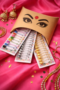 Bindee 'Essential Safety-pin kit' with gold, silver and multicolor safety pin cards on a pink background.