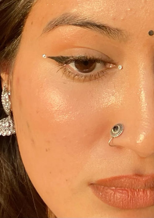 Close-up of a person's face with decorative crystal bindis around the eyes. 